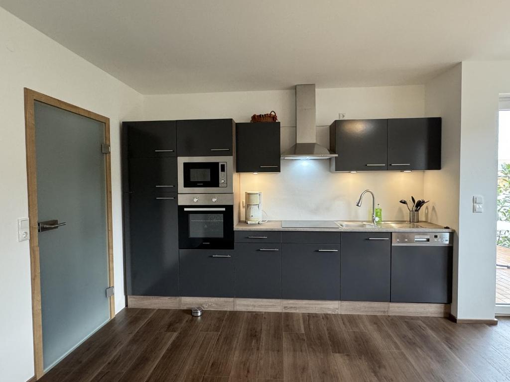 an empty kitchen with black cabinets and appliances at Ferienwohnung Adelsried 1 in Adelsried