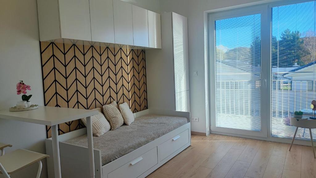 Una habitación con un banco con una mesa y una ventana. en Modern studio in a residence with parking, en Myjava