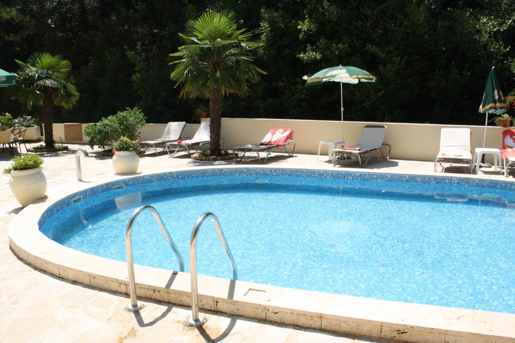 a large swimming pool with chairs and an umbrella at Hotel Danica in Petrovac na Moru
