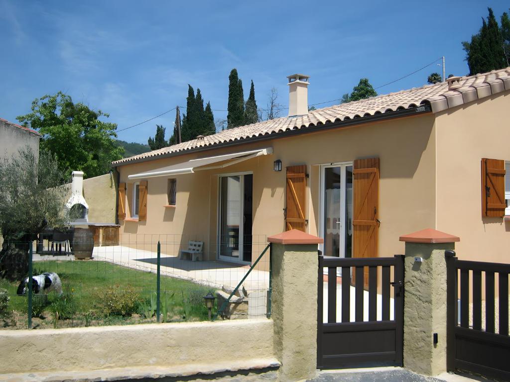 a house with a gate and a dog in the yard at Maguy Les Oliviers in Couiza