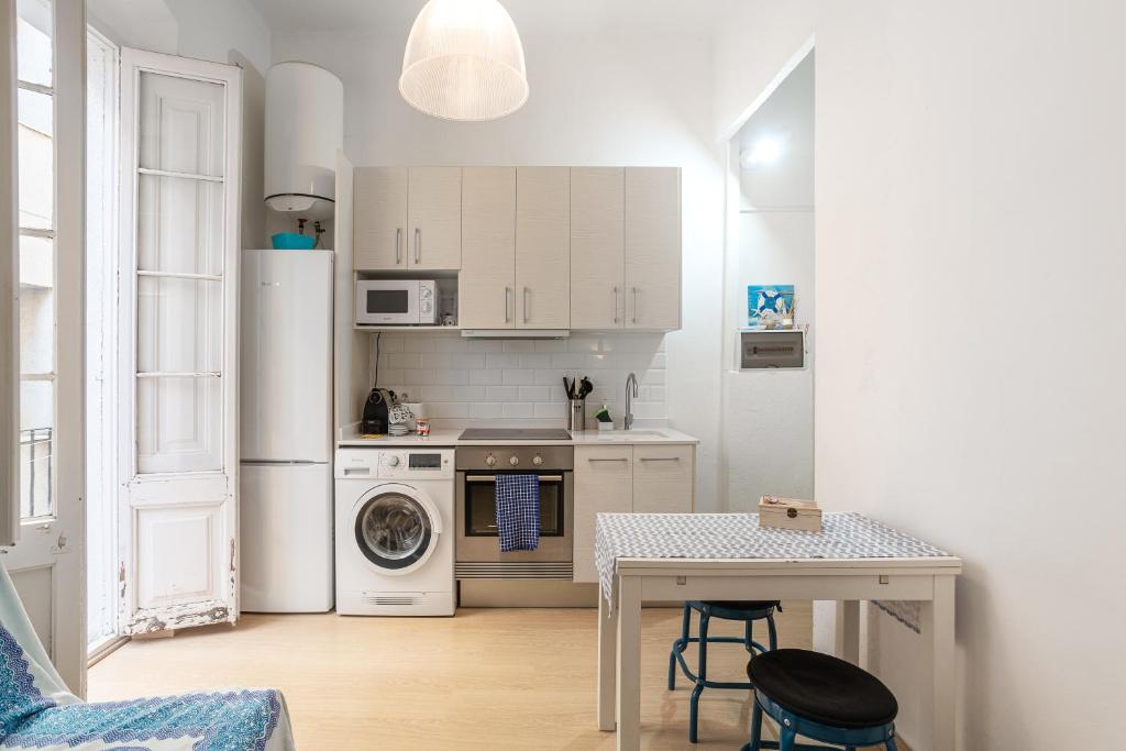a kitchen with a table and a white refrigerator at Cozy Apartment Blanes in Blanes