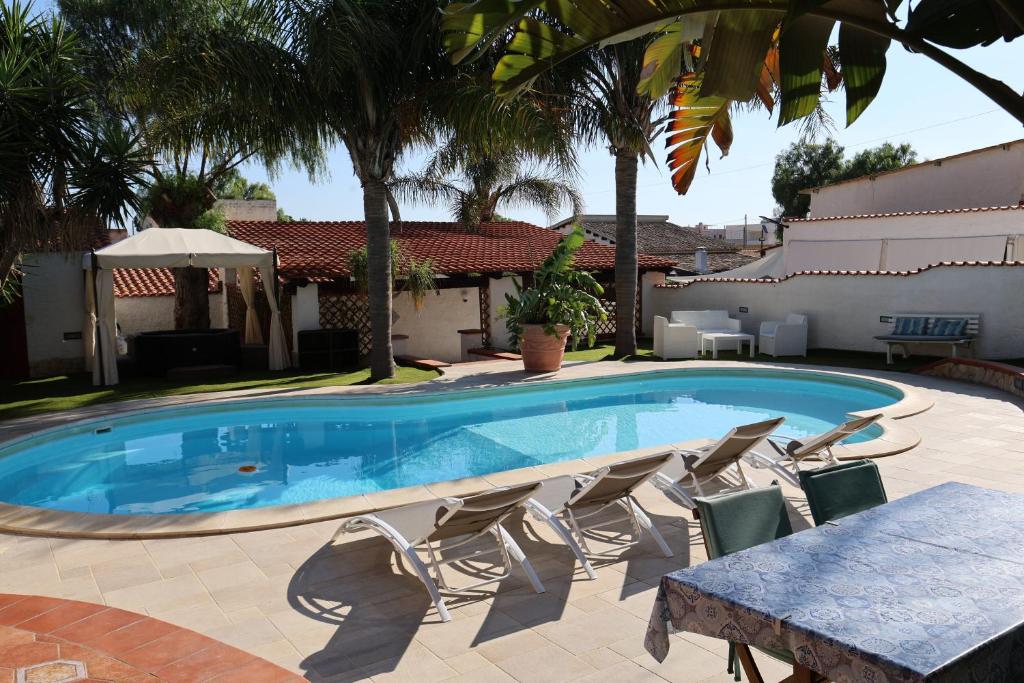 - une piscine avec des chaises et une table en face d'une maison dans l'établissement RIFLESSI D'AZZURRO - la vacanza dei tuoi sogni, à Castelvetrano