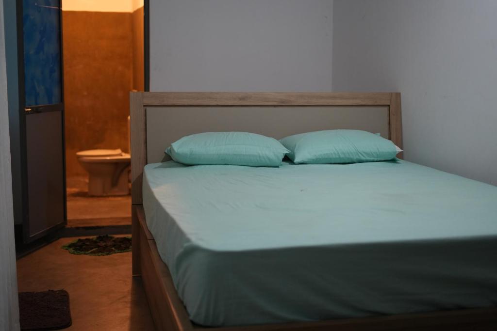 a bed with two blue pillows on top of it at Sri Vishwa Buddha MUni in Kalagedihena