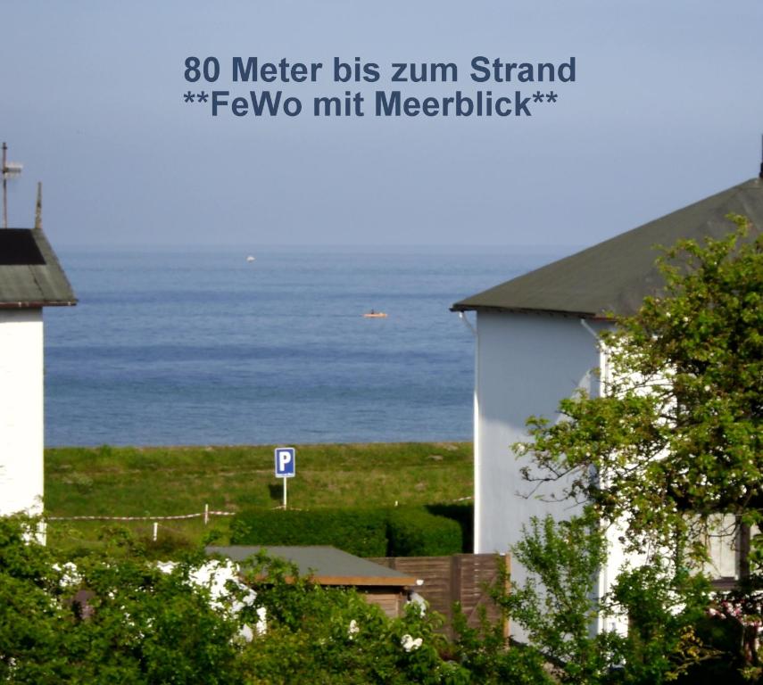 a white building with the ocean in the background at Haus Seeblick in Dahme