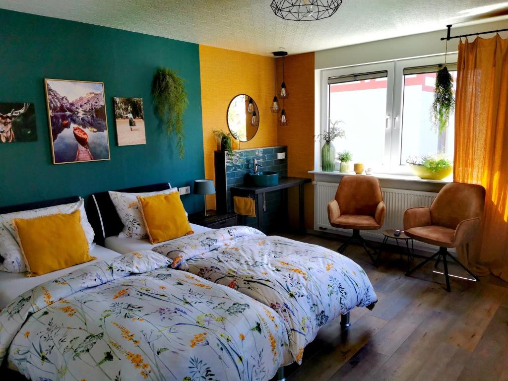 a bedroom with a bed and two chairs and a window at Moderne Ferienwohnung Am Flohbach 1 in Floh