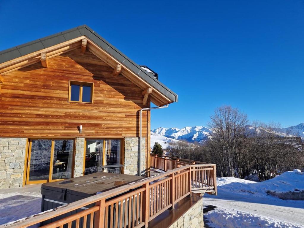 a log cabin with a deck in the snow at Chalet Salt Lake in La Toussuire