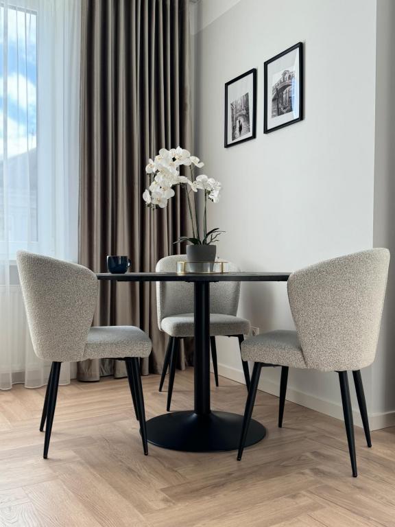 a dining room table with two chairs and a vase with flowers at City Centre Apartment with Cathedral View, Self Check-in in Šiauliai