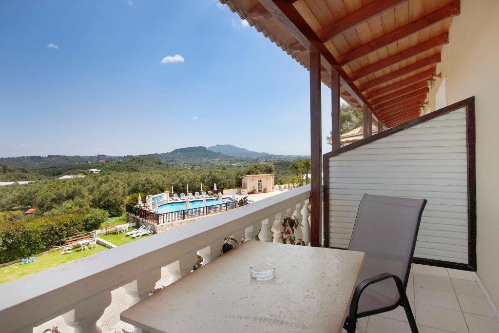 balcón con mesa y vistas a la piscina en Zante View Family Studio 4, en Tsilivi