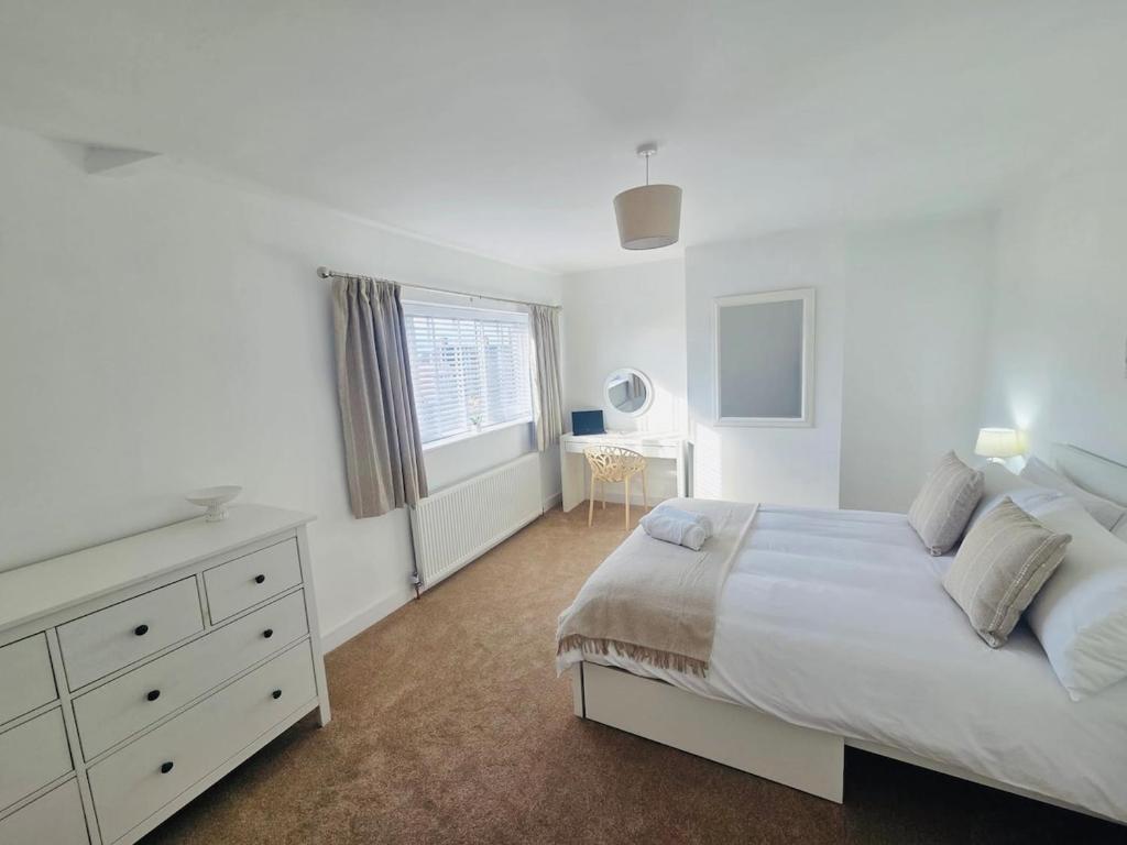 - une chambre blanche avec un grand lit et une commode dans l'établissement 3 Bedroom Village Stay - Comfort & Charm in Yorkshire, à Kippax