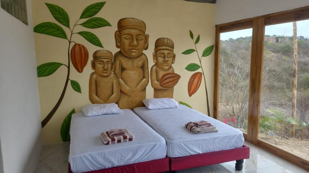 a bedroom with two beds with a mural on the wall at Le jardin in Puerto López