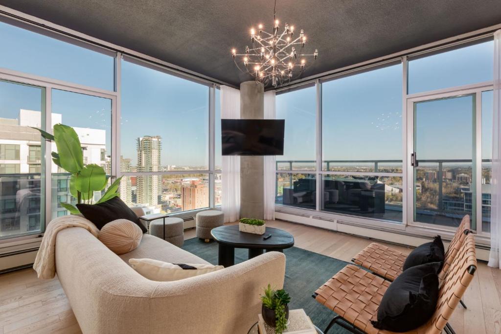 a living room with a couch and chairs and large windows at 2 Storey Penthouse Panoramic Views Parking Stampede in Calgary