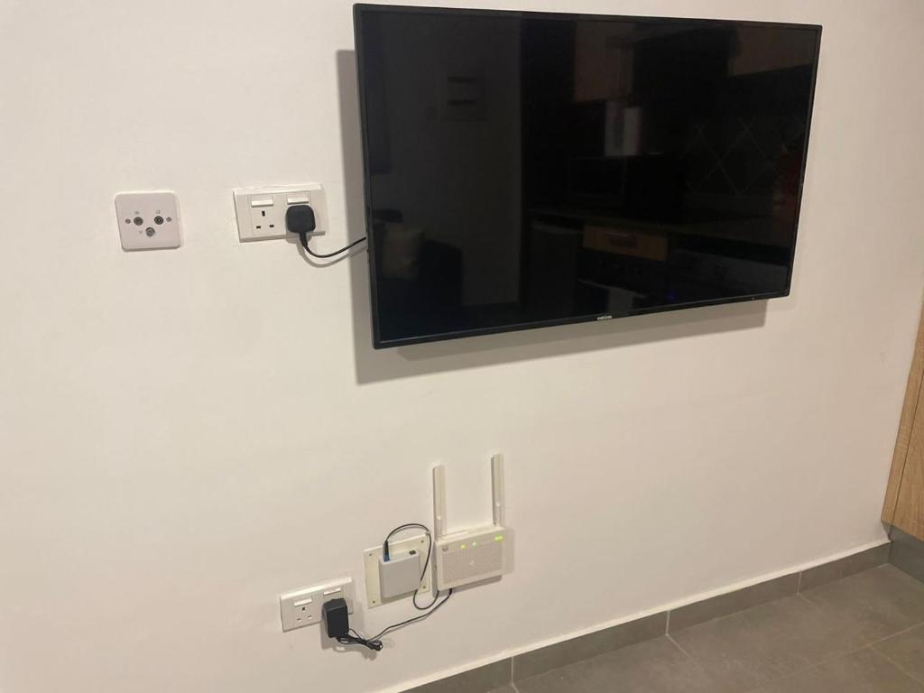 TV de pantalla plana en la pared del baño en Oasis Park Residences, en Accra