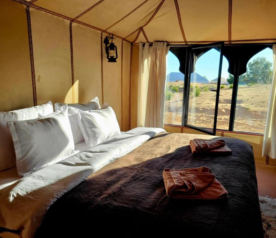 a bedroom with a large bed with a large window at Celestial luxury Camp in Merzouga