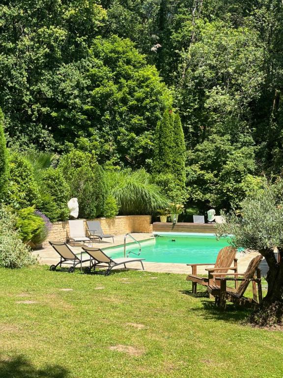 a swimming pool with two benches and a picnic table at Les Ocelles De Sarlat in Sarlat-la-Canéda