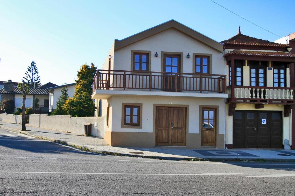 a white house with a balcony on a street at Casa Do Cais - Torreira in Torreira