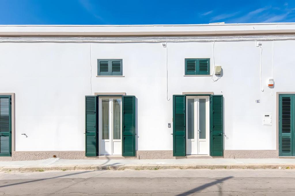 a white building with green shutters on it at Casa Don Paolo in Alessano