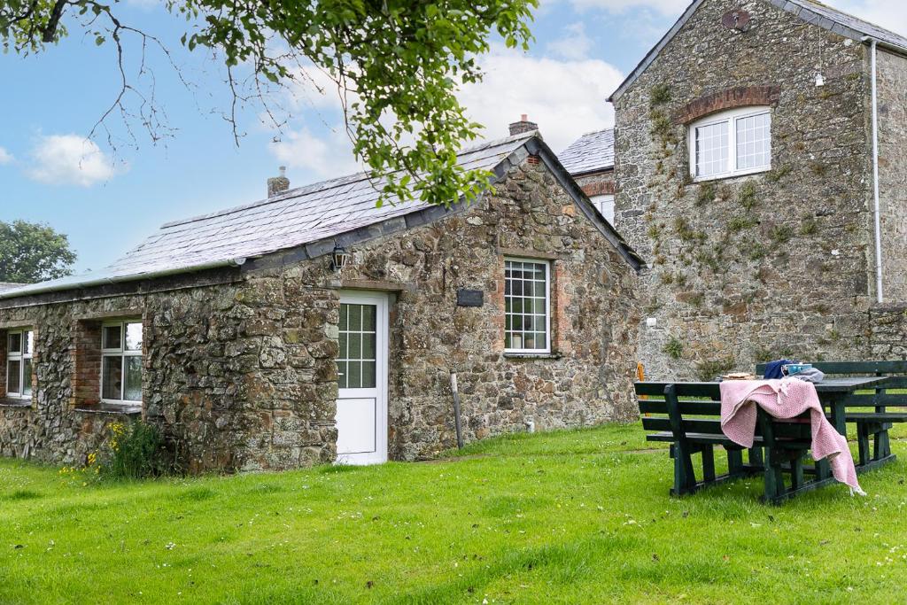 a stone house with a bench in front of it at Fuchsia Cottage in Saint Endellion