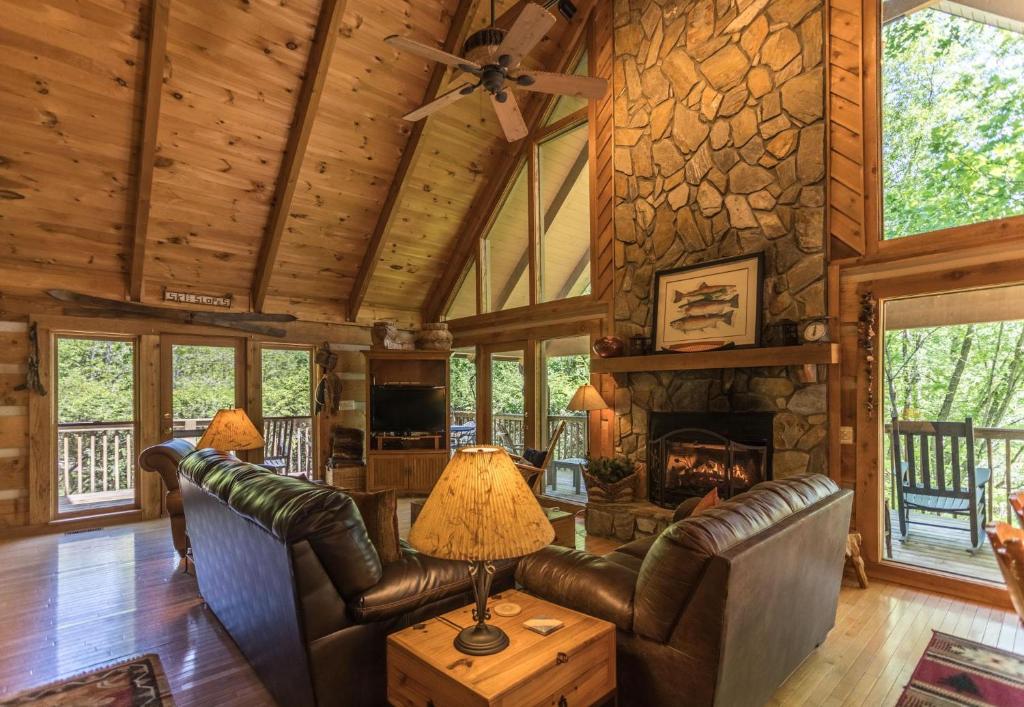 a living room with leather furniture and a stone fireplace at Almost Heaven in Sugar Grove