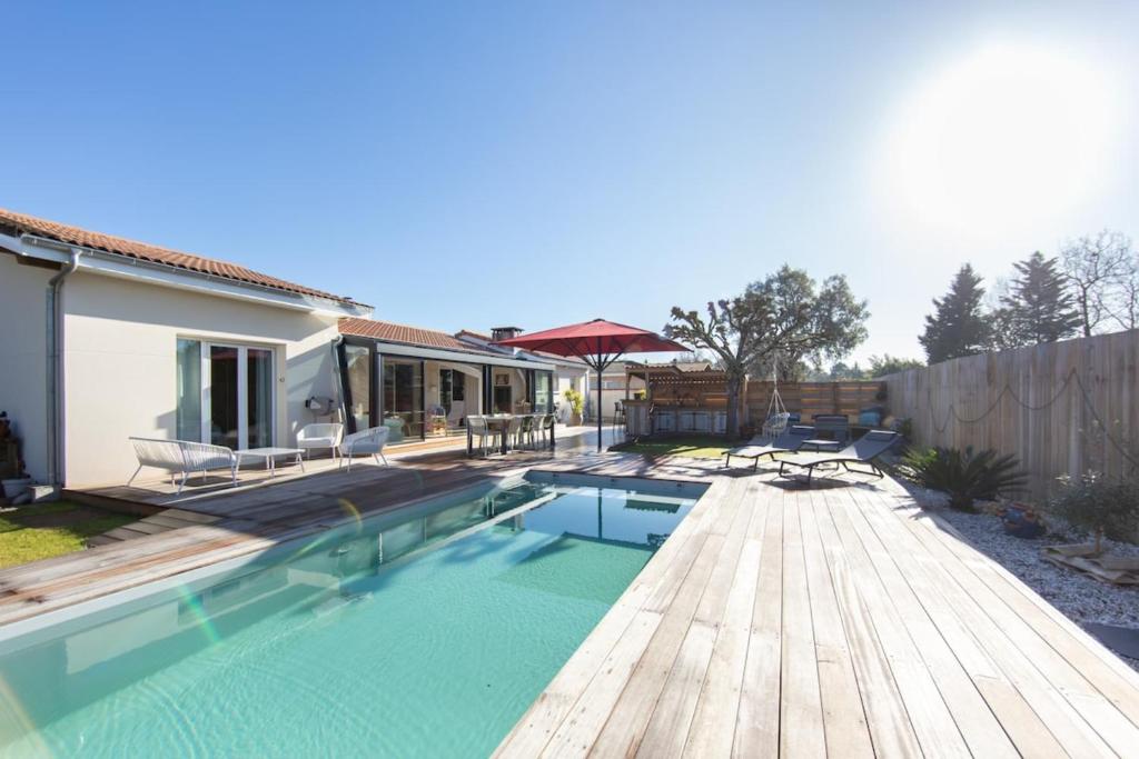 een achtertuin met een zwembad en een houten terras bij Villa Goya in Ares with private pool in Arès
