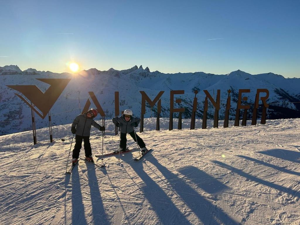 two people on skis in the snow near a sign at Résidence Les Lumières des Neiges et parking in Valmeinier