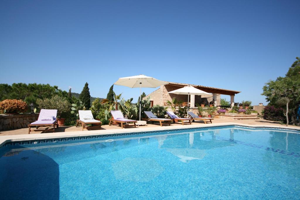 a swimming pool with chairs and an umbrella at Can Ramon in Caʼs Concos