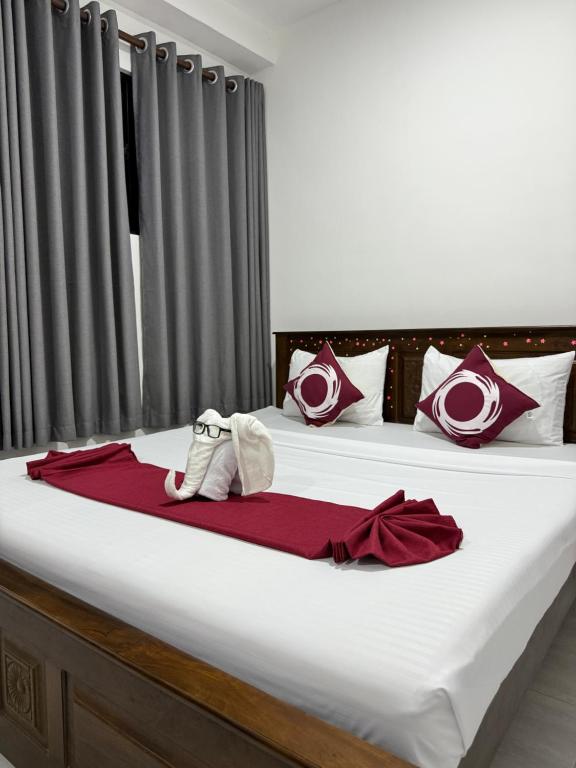 een slaapkamer met een groot bed met rode en witte kussens bij Dewliya Rest in Galle