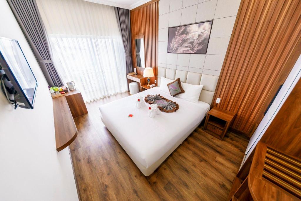 Un dormitorio con una cama blanca en una habitación. en Wisteria Hotel Dalat, en Da Lat
