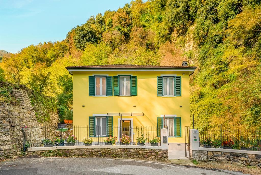 a yellow house with green shutters on a hill at Il sentiero b&b in La Spezia