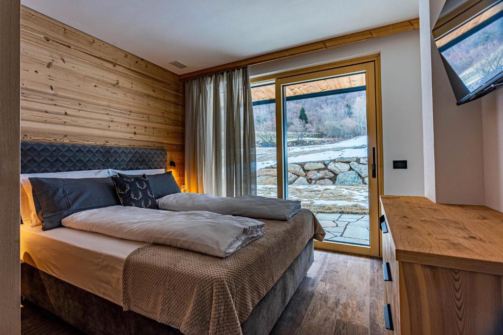 a bedroom with a bed and a large window at Arnica Alpin Lodge in Cavedago