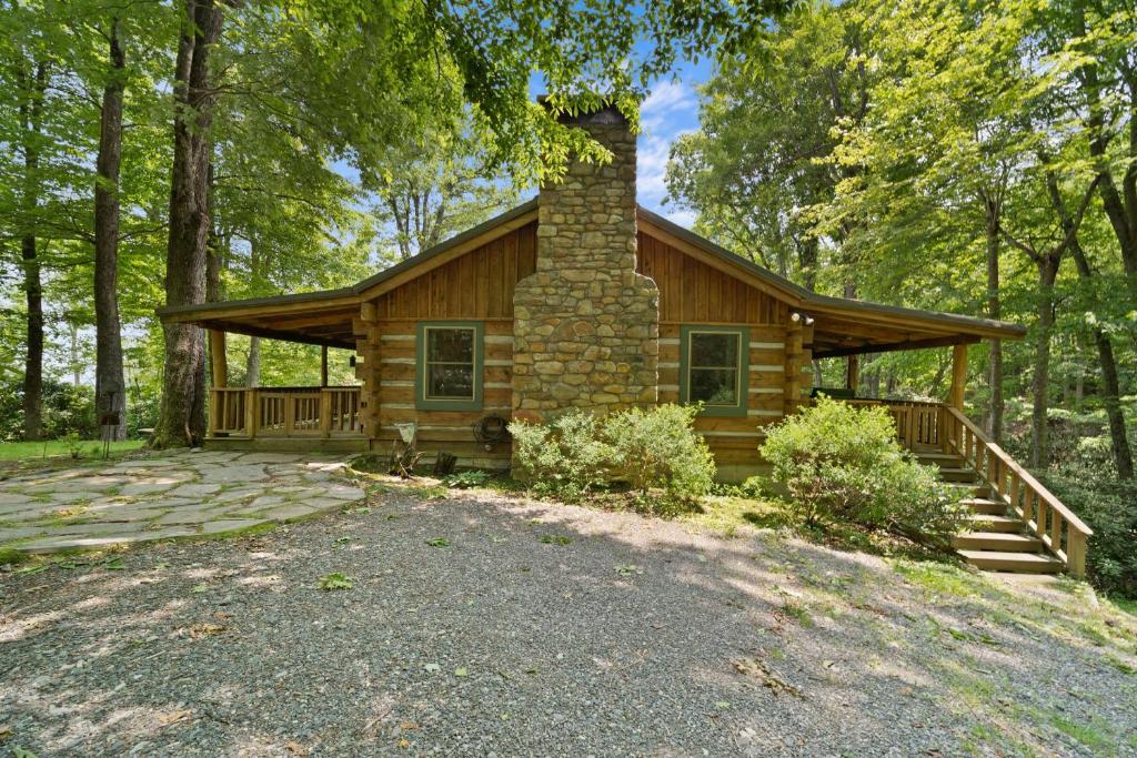a log cabin with a chimney in the woods at Natures Call in Boone