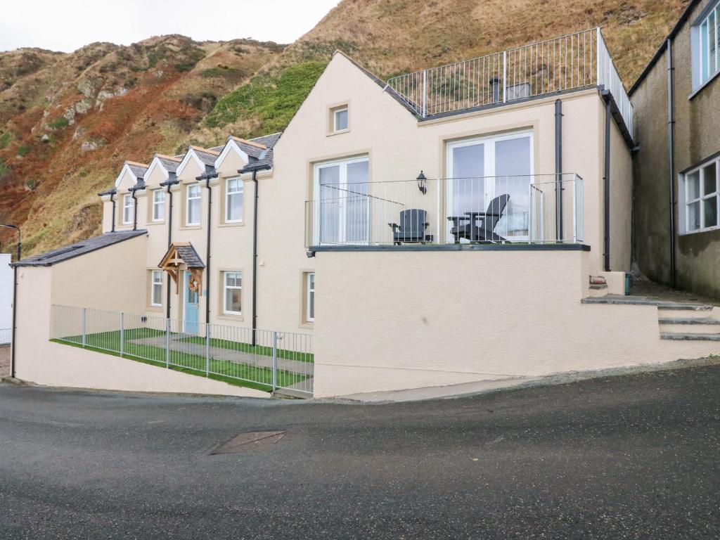 a house with a balcony with two chairs on it at The Old Kipper Hoose in Gardenstown