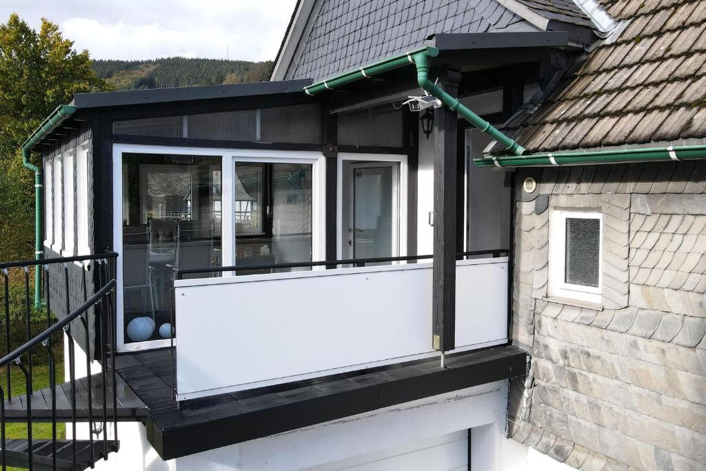 Cette maison dispose d'une porte blanche et d'un balcon. dans l'établissement Ferienwohnung Blum, à Schmallenberg