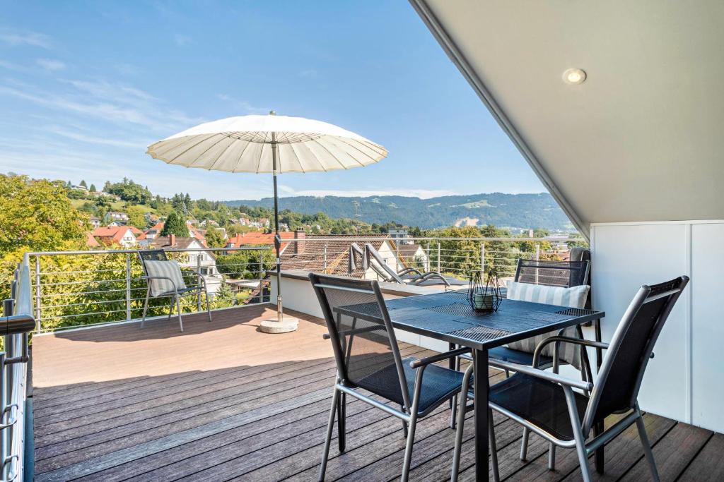 a table and chairs on a balcony with an umbrella at Pfänderblick in Lindau
