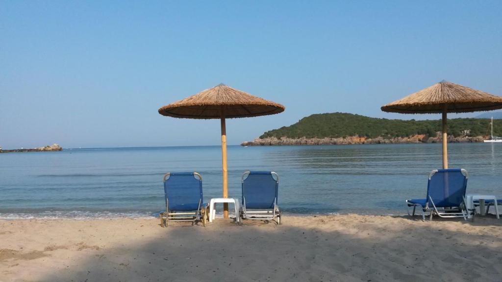 two chairs and two umbrellas on a beach at Splantza Apartments in Ammoudia