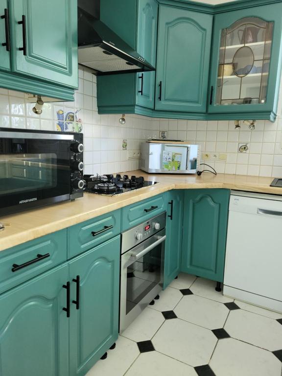 a kitchen with blue cabinets and a stove top oven at Le gite d 'Amélie maison rénovée 6 couchages 2 salles de bains in Célon