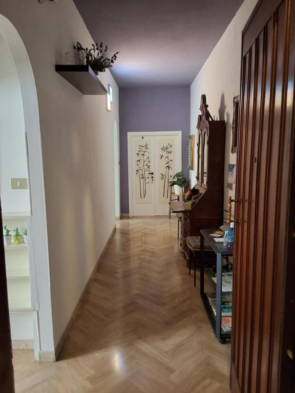 ein Zimmer mit einem Flur mit Holzboden und ein Zimmer mit einem Tisch in der Unterkunft Mascagni Rooms in Florenz