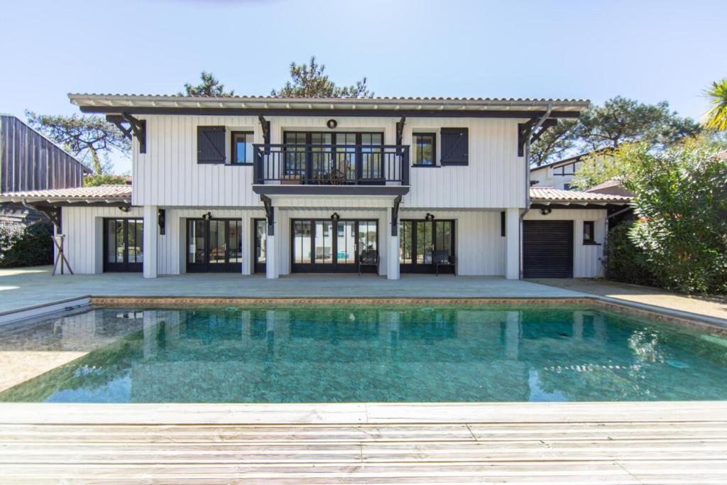 a house with a swimming pool in front of a house at Villa Du Phare avec piscine chauffée pour 14 perso in Cap-Ferret