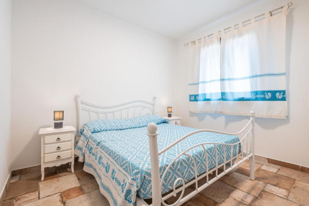 a white bedroom with a bed and a window at Villa Giardino in Villasimius