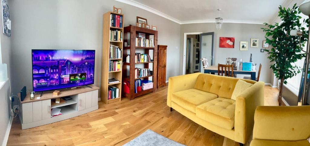 サウスポートにあるSouthport-Birkdale Luxury Havenのリビングルーム(黄色のソファ、薄型テレビ付)