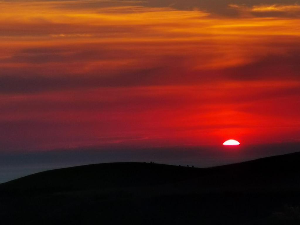 a sunset with the sun setting over a hill at Caol Ila - Lodge 8 in Stranraer