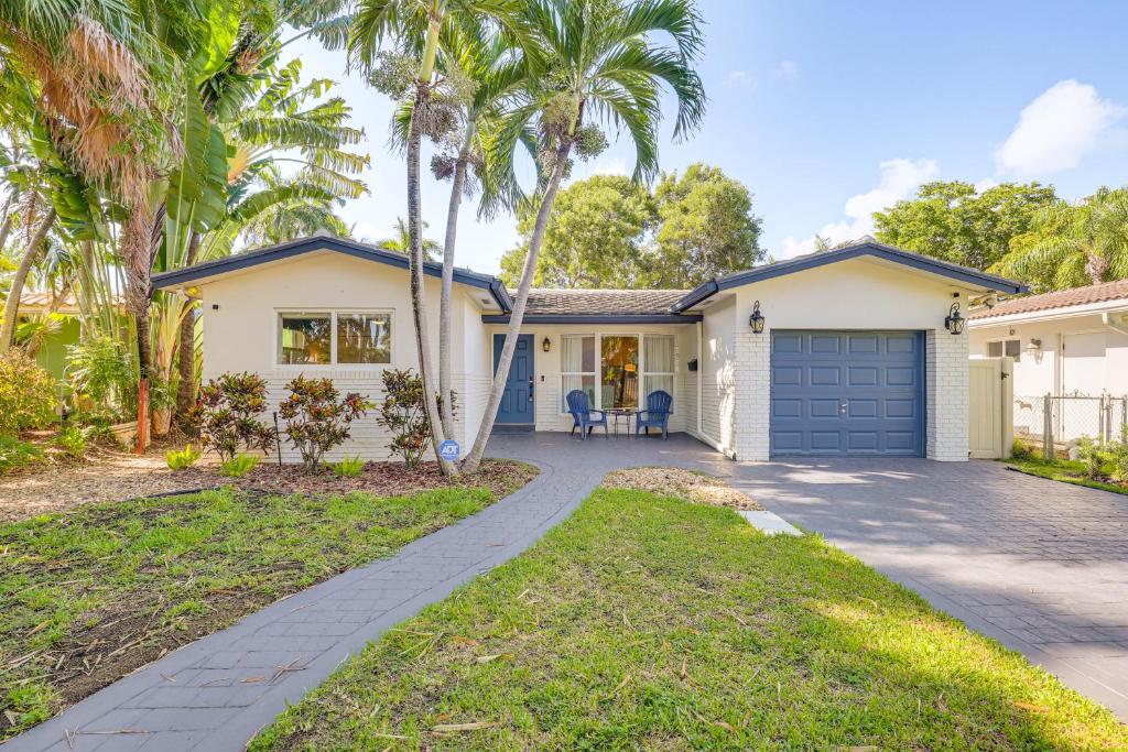 a white house with a blue garage and palm trees at Spacious Yard, Near Golf Modern Home in Hollywood in Hollywood Beach