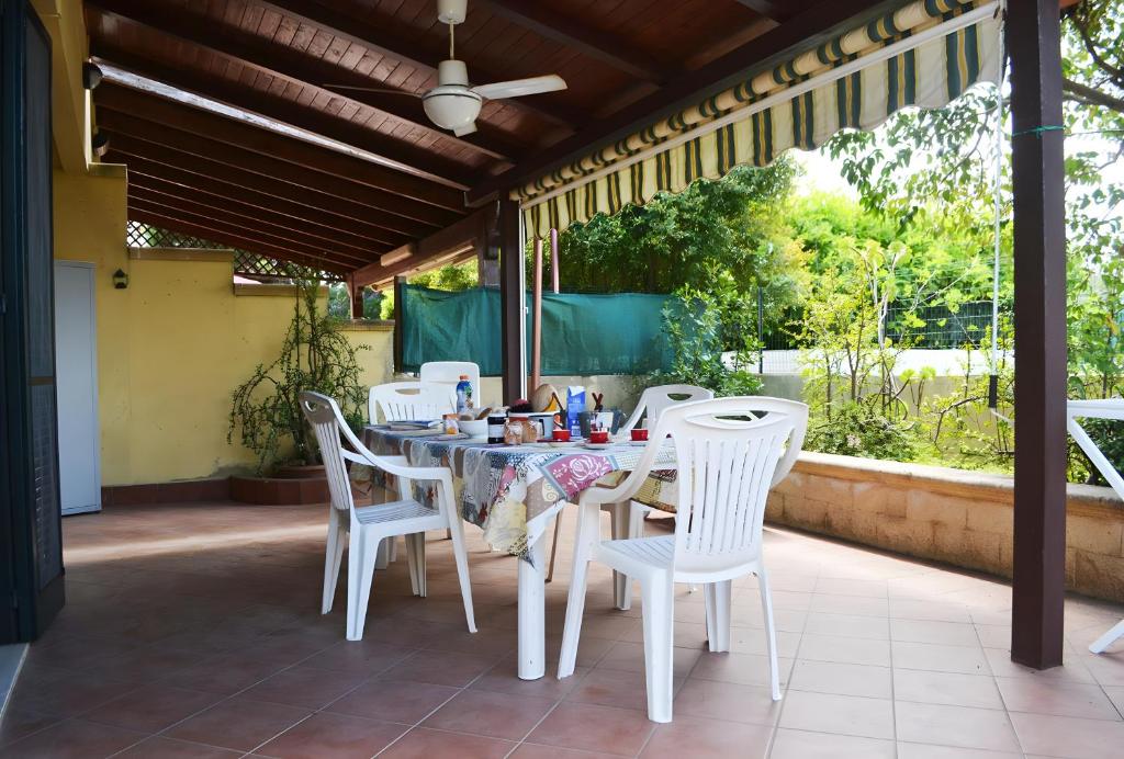 een eettafel en stoelen op een patio bij Pt63 Casa a T dell Orso con veranda in Melendugno