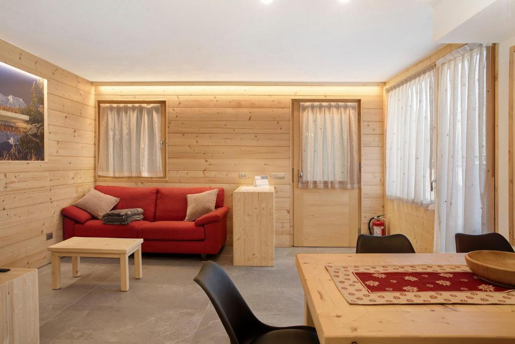 キエーザ・イン・ヴァルマレンコにあるAppartamento Stella Alpinaの赤いソファとテーブルのあるリビングルーム