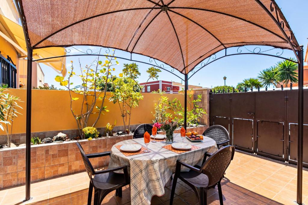 un patio con tavolo, sedie e ombrellone di Casa Vacacional Golfin ad Arona