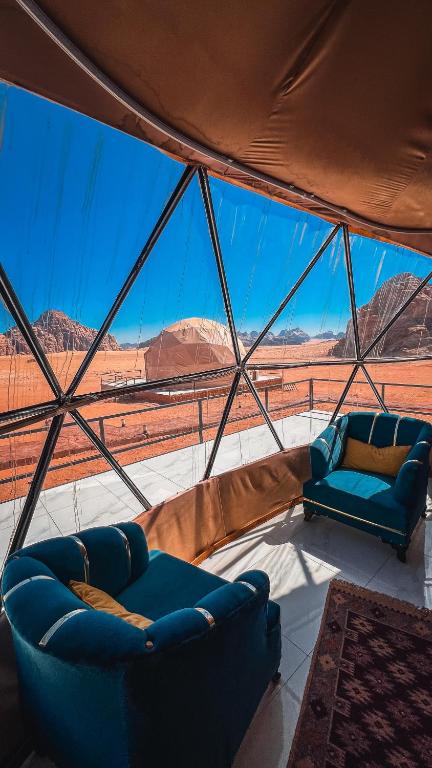a tent with two couches and a view of the desert at RUM FLORAA LUXURY CAMp in Wadi Rum