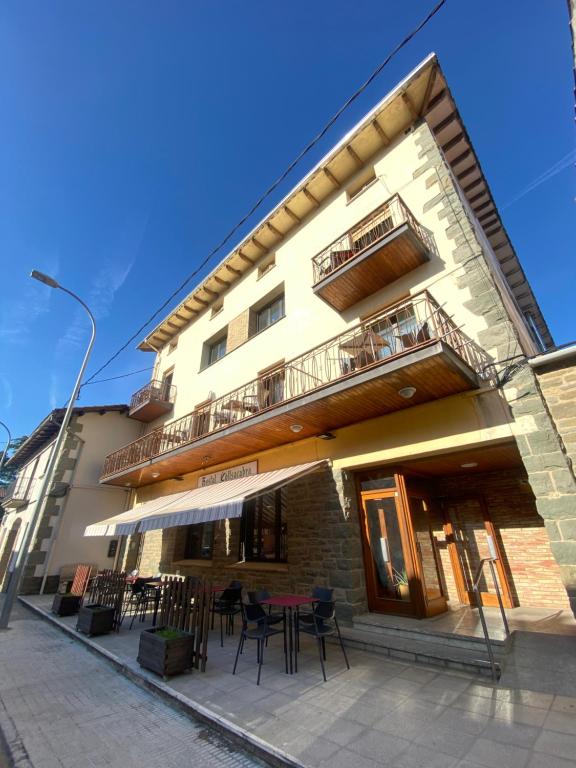 a building with tables and chairs in front of it at Hostal Collsacabra in L’ Esquirol