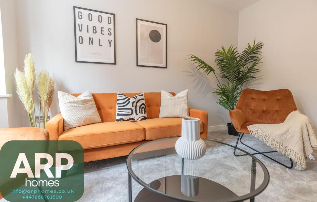 a living room with an orange couch and a glass table at Green Park House, Private Garage and Parking in Coventry