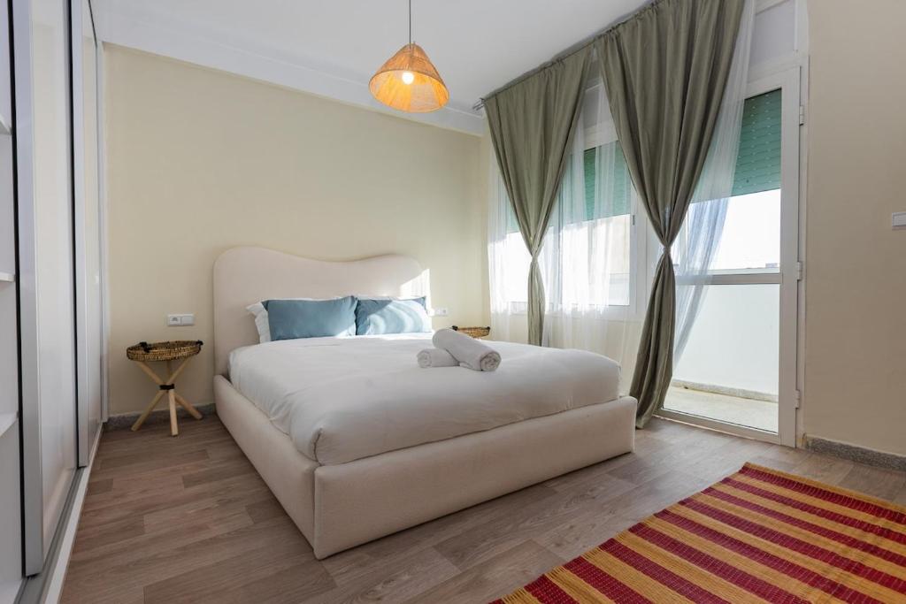 a bedroom with a white bed and a large window at Élégant 2BR au cœur de Hassan by MERAT HOME in Rabat