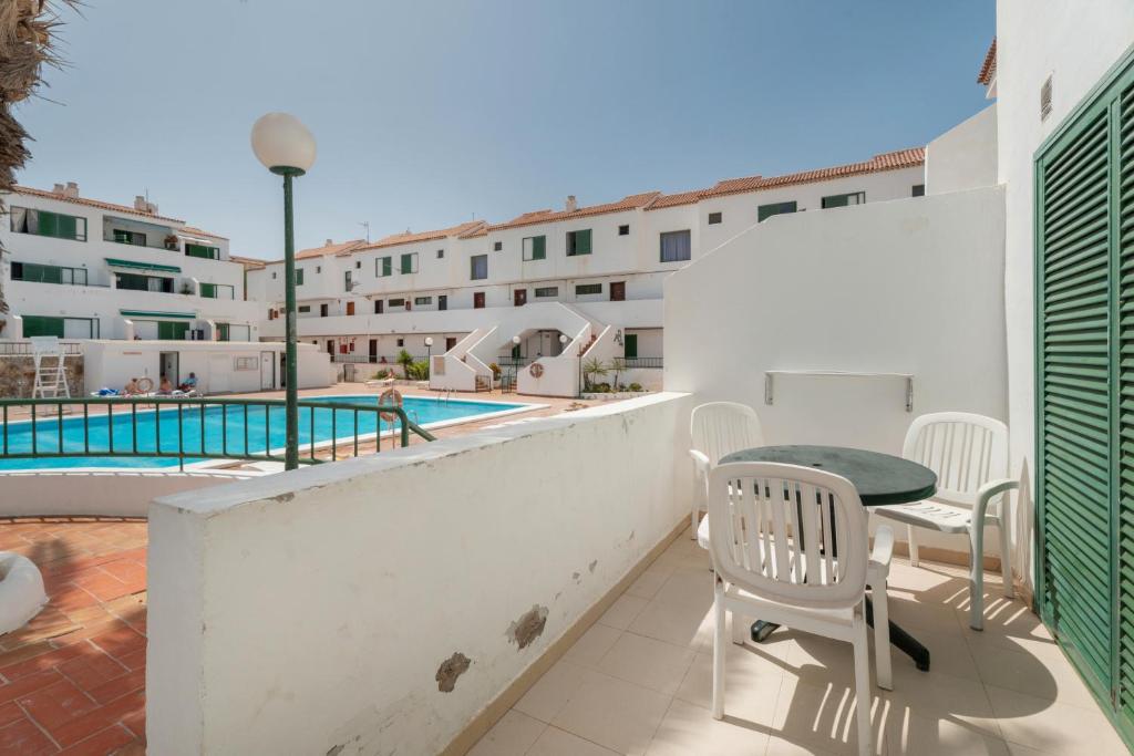 een balkon met een tafel en stoelen naast een zwembad bij Alondras Apartamento E107 in Costa Del Silencio
