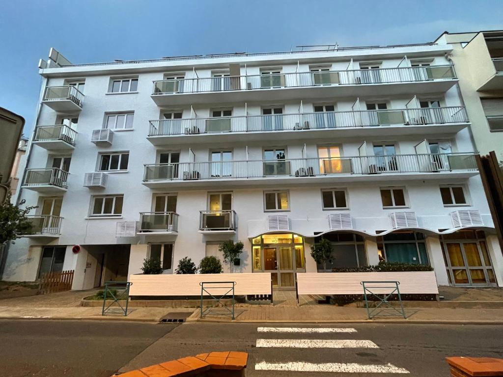 阿梅利莱班帕拉勒达Aparthotel New Palmarium的前面有长椅的白色建筑